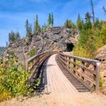 The Kettle Valley Rail Trail curving into a rock face tunnel.