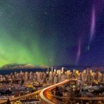 The aurora borealis illuminating the night sky over the Vancouver skyline.