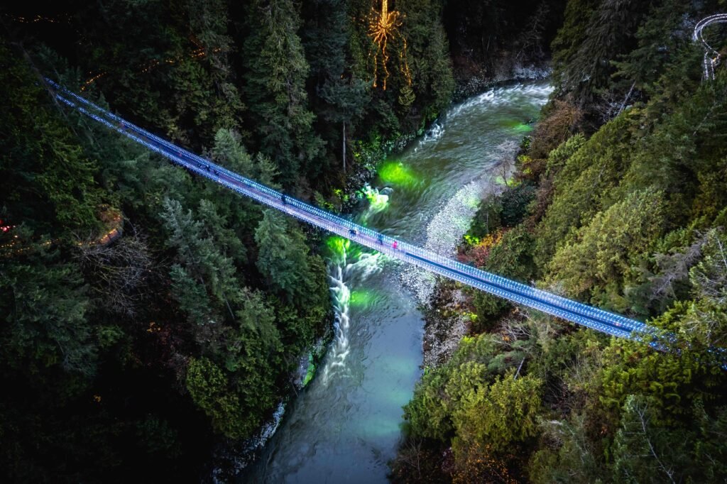 Christmas in British Columbia - Capilano Suspension Bridge illuminated with blue lights during Canyon Lights festival over forest canyon