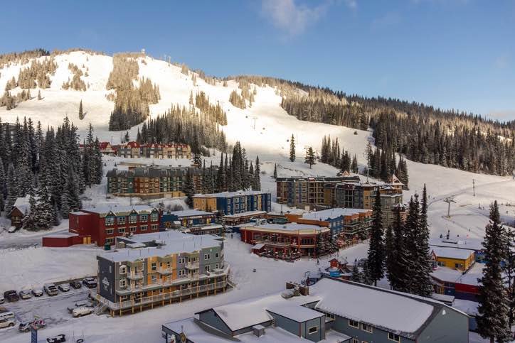Skiing the Thompson Okanagan at Silver Star Mountain Resort showcasing vibrant Victorian-style buildings at the village base with pristine ski slopes and evergreen forests in winter