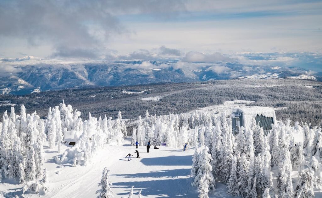 Skiing the Thompson Okanagan at Sun Peaks Resort with skiers descending through spectacular snow-laden ghost trees and panoramic mountain vistas under clear winter skies