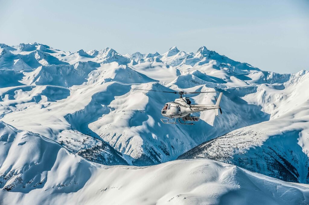Last Frontier Heliskiing helicopter flying over the vast glaciated Coast Mountains terrain in Northern British Columbia, showcasing the world's largest heli-ski tenure