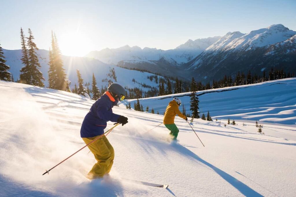 Valentine’s Weekend in British Columbia: Couple skiing together on a sunlit powder slope in Whistler Blackcomb during Valentine’s Day weekend, surrounded by snow-covered mountains in British Columbia.