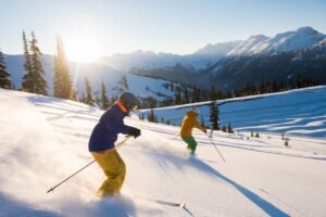 Valentine’s Weekend in British Columbia: Couple skiing together on a sunlit powder slope in Whistler Blackcomb during Valentine’s Day weekend, surrounded by snow-covered mountains in British Columbia.