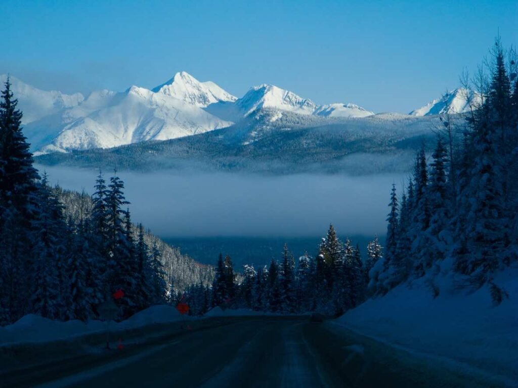 Sea-to-Sky Highway in Winter: Dramatic winter mountain view with fog-filled valley below snow-capped peaks and forested slopes viewed from Sea-to-Sky Highway in British Columbia