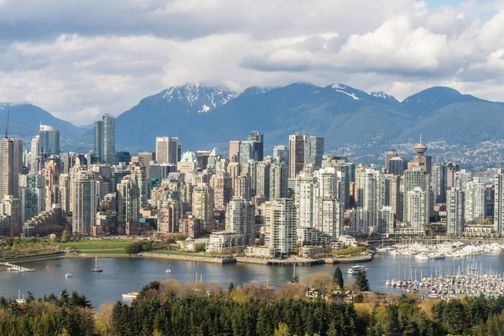 Winter cityscape of Vancouver showing downtown buildings, marina, and snow-capped mountains in British Columbia