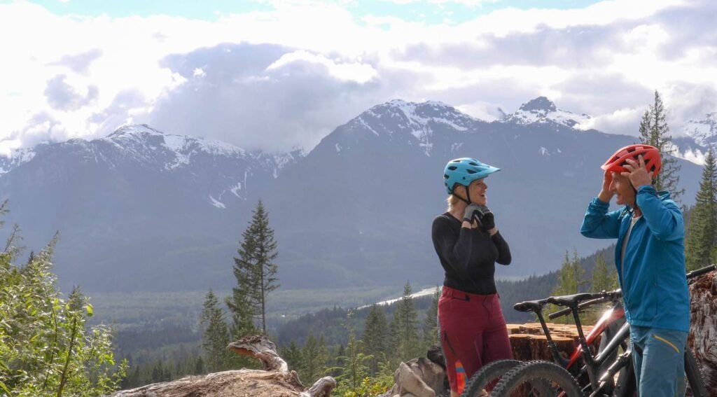Mountain bikers with snow-capped peaks during British Columbia shoulder season adventures