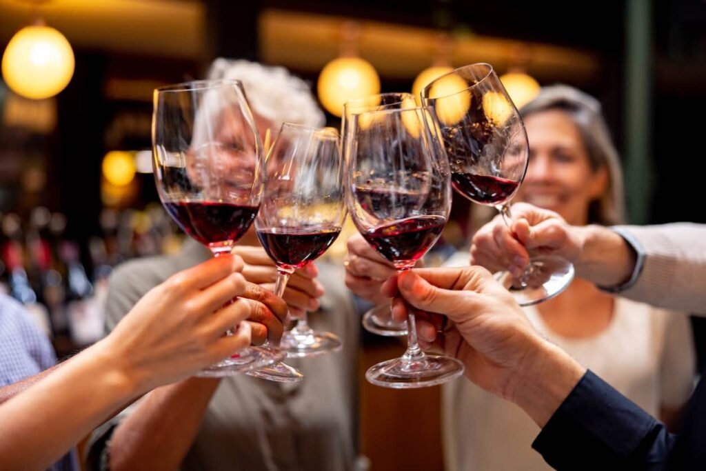 A close-up of a group of friends clinking glasses of red wine during a spring tasting in Okanagan wine country.